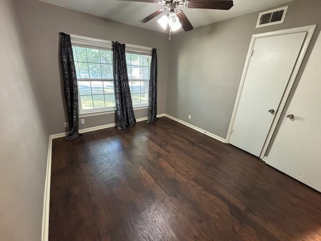 empty room with ceiling fan and dark hardwood / wood-style flooring