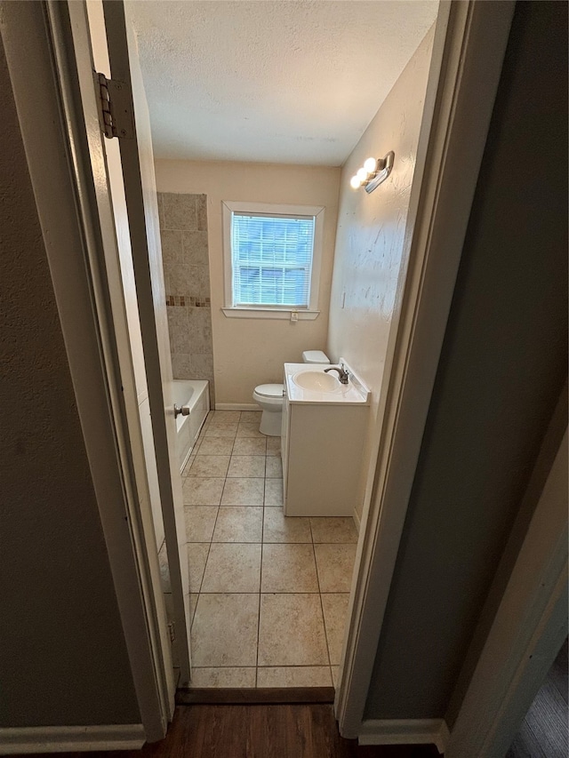 full bathroom with independent shower and bath, a textured ceiling, toilet, vanity, and tile patterned flooring