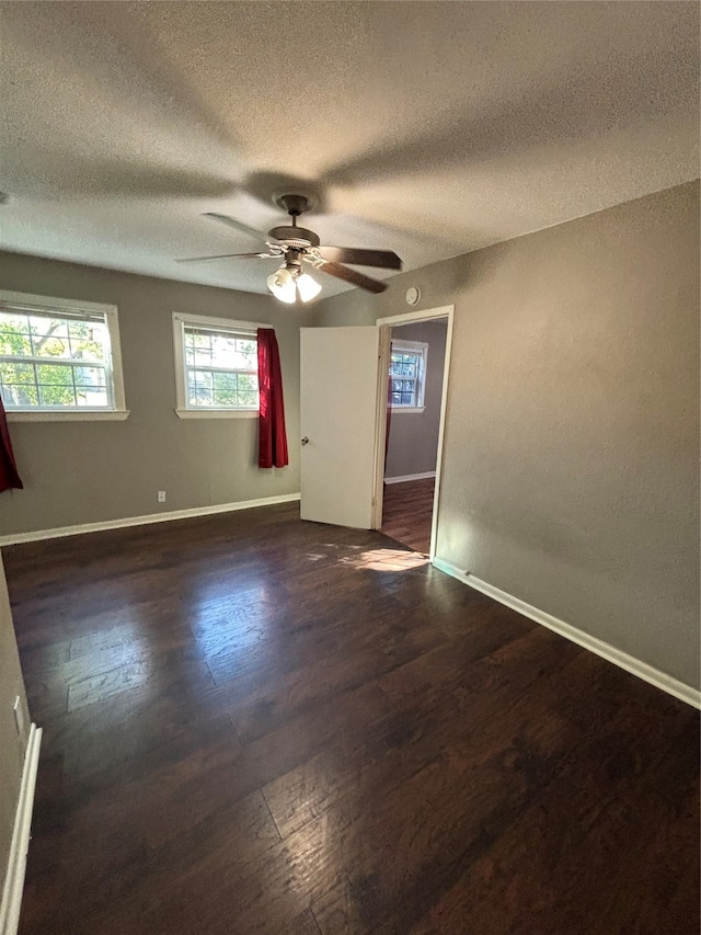 empty room with dark wood-type flooring, ceiling fan, and a textured ceiling