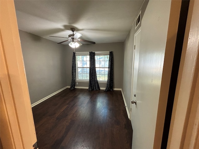 empty room with dark wood-type flooring and ceiling fan