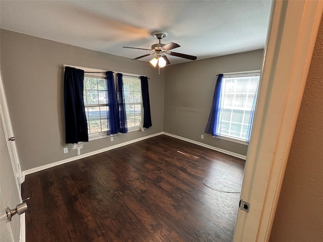 empty room featuring a textured ceiling, ceiling fan, dark wood-type flooring, and a wealth of natural light