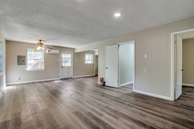 unfurnished living room with a textured ceiling, dark hardwood / wood-style flooring, ceiling fan, a wall mounted AC, and electric panel