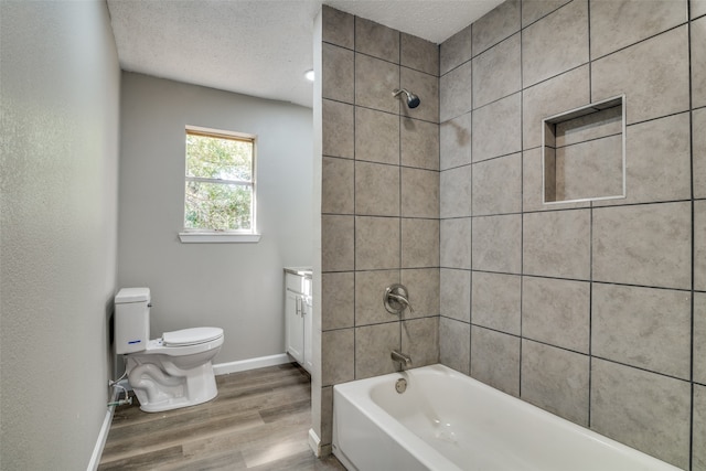 full bathroom with toilet, wood-type flooring, tiled shower / bath, vanity, and a textured ceiling