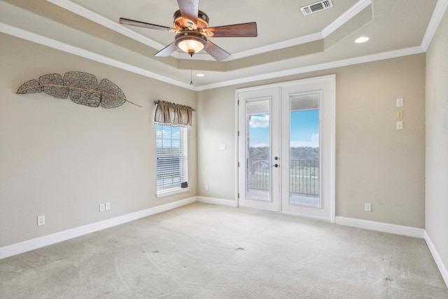 unfurnished room featuring light carpet, ceiling fan, a tray ceiling, crown molding, and french doors