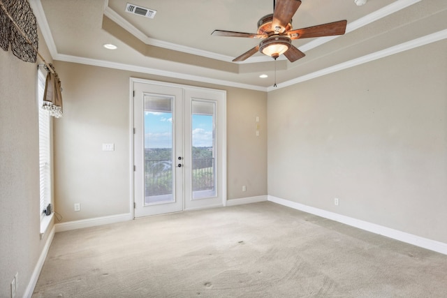 carpeted spare room featuring french doors, ceiling fan, ornamental molding, and a tray ceiling