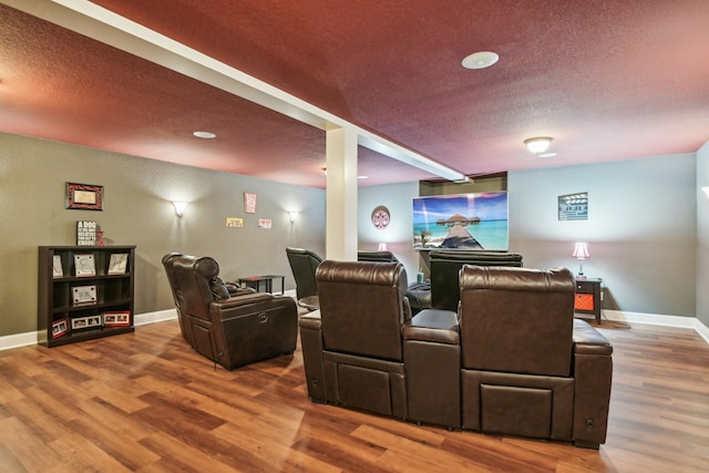 cinema room with wood-type flooring and a textured ceiling