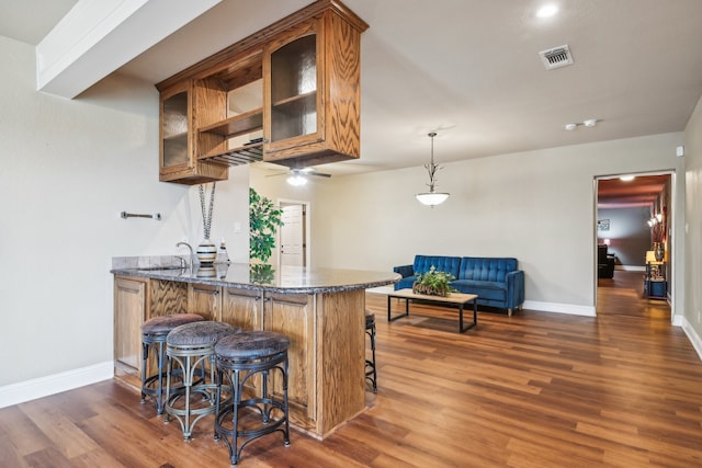 kitchen with kitchen peninsula, dark hardwood / wood-style floors, and a kitchen breakfast bar