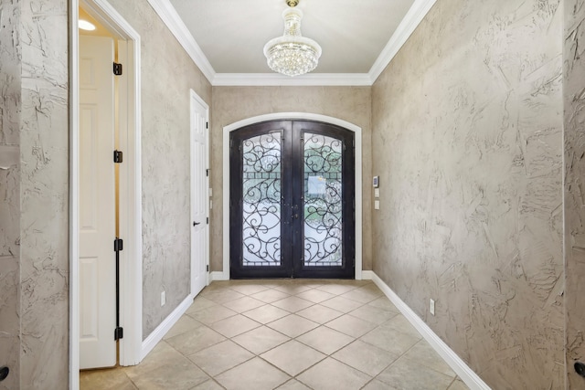 tiled entrance foyer featuring french doors, ornamental molding, and a notable chandelier