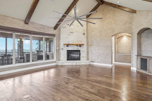 unfurnished living room with beam ceiling, ceiling fan, high vaulted ceiling, wood-type flooring, and a fireplace