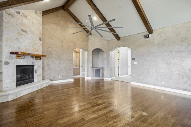 unfurnished living room with high vaulted ceiling, beamed ceiling, and hardwood / wood-style floors