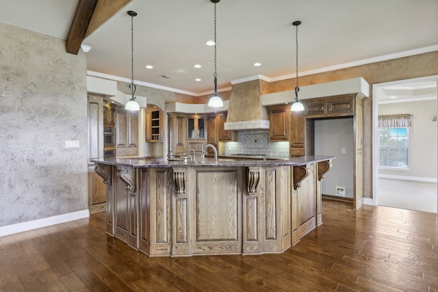 kitchen featuring a large island with sink, a breakfast bar area, dark hardwood / wood-style floors, and hanging light fixtures