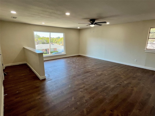 empty room featuring a wealth of natural light, dark hardwood / wood-style flooring, and ceiling fan