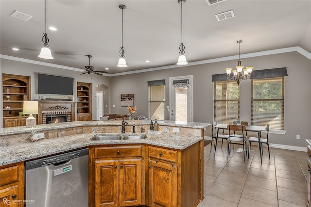 kitchen with light tile patterned floors, stainless steel dishwasher, a brick fireplace, sink, and decorative light fixtures