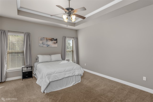 bedroom featuring ceiling fan, a raised ceiling, and light carpet