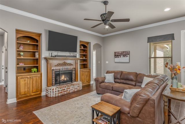 living room featuring ornamental molding, dark hardwood / wood-style floors, a fireplace, and ceiling fan