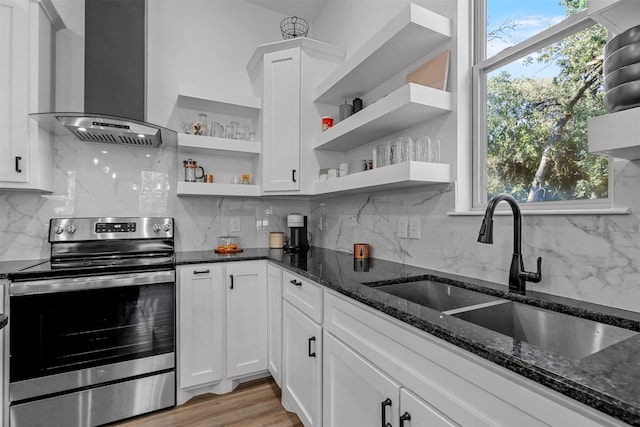 kitchen with wall chimney exhaust hood, white cabinetry, tasteful backsplash, and electric stove