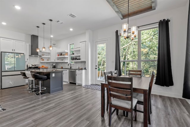 dining area featuring a notable chandelier, hardwood / wood-style flooring, sink, and a raised ceiling