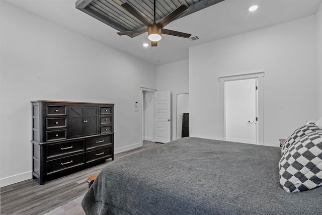 bedroom with a towering ceiling, ceiling fan, and wood-type flooring