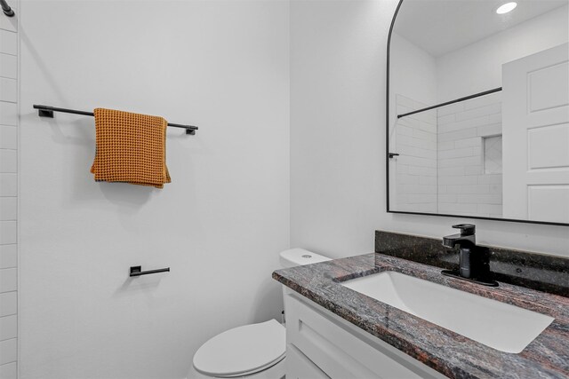 bathroom with vanity, toilet, and a tile shower