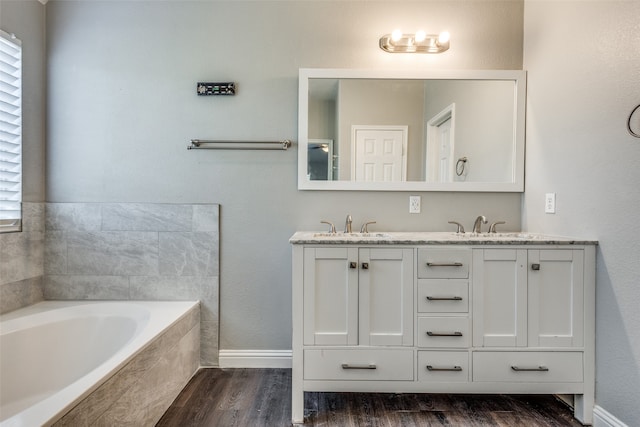 bathroom featuring vanity, hardwood / wood-style flooring, a relaxing tiled tub, and a wealth of natural light