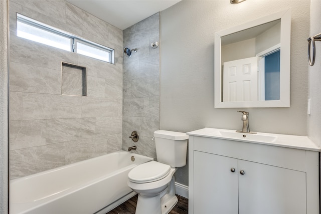 full bathroom featuring tiled shower / bath, vanity, wood-type flooring, and toilet