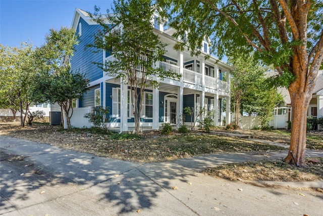 view of front of property featuring covered porch, cooling unit, and a balcony