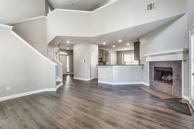 unfurnished living room with dark wood-type flooring, a fireplace, and a towering ceiling