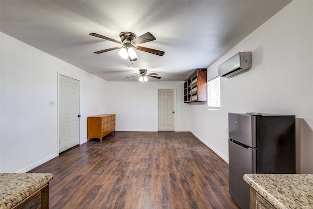 kitchen featuring a wall mounted air conditioner, ceiling fan, stainless steel fridge, and dark hardwood / wood-style flooring