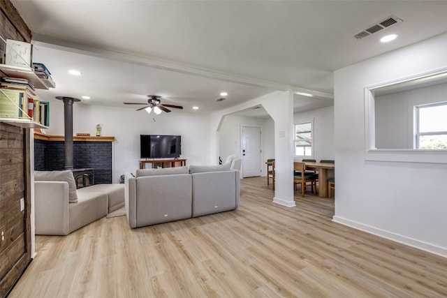 living room featuring light wood-type flooring, a wood stove, and a wealth of natural light