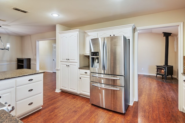 kitchen with stainless steel fridge, white cabinets, dark stone counters, and dark hardwood / wood-style flooring