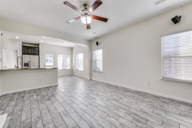 unfurnished living room featuring light wood-type flooring, ceiling fan, and sink