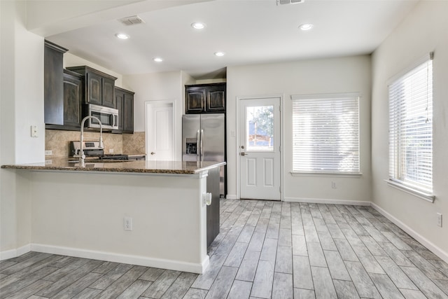 kitchen with dark stone countertops, appliances with stainless steel finishes, and a healthy amount of sunlight