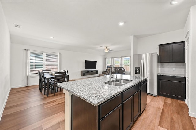 kitchen with sink, ceiling fan, an island with sink, backsplash, and appliances with stainless steel finishes