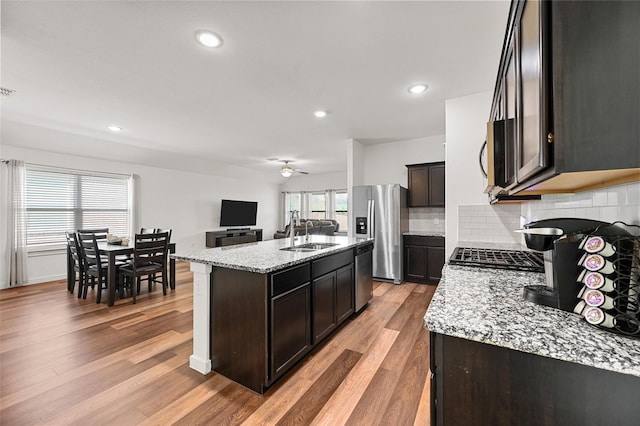 kitchen with sink, light stone counters, backsplash, a kitchen island with sink, and appliances with stainless steel finishes