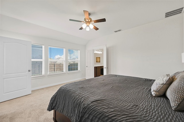 bedroom with lofted ceiling, ensuite bathroom, light carpet, and ceiling fan