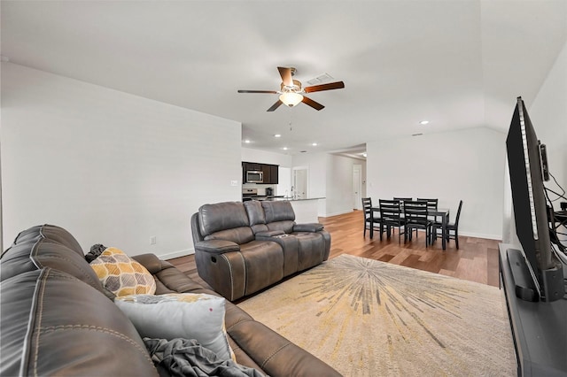 living room featuring light wood-type flooring, ceiling fan, and vaulted ceiling