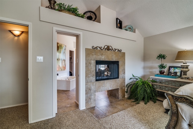 bedroom with connected bathroom, a textured ceiling, a tile fireplace, and carpet