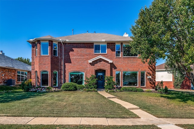 view of front facade with a chimney, brick siding, and a front yard