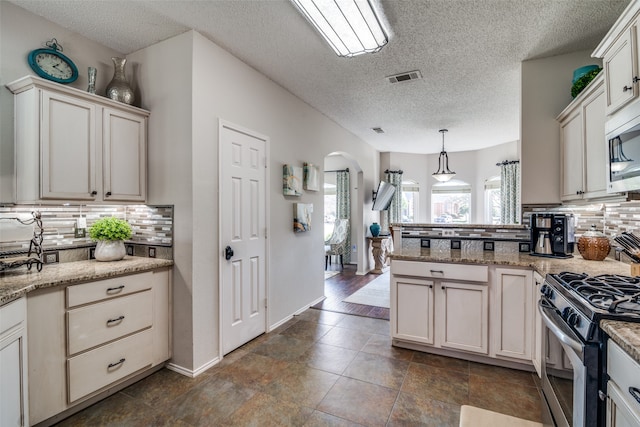 kitchen with backsplash, appliances with stainless steel finishes, pendant lighting, and light stone counters