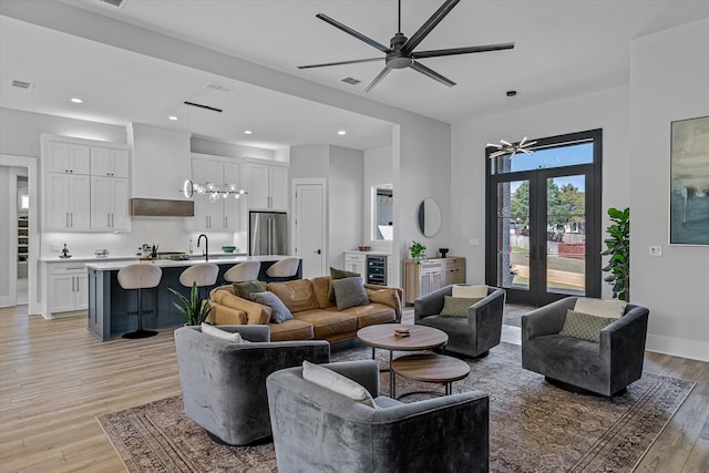 living room with light hardwood / wood-style flooring, sink, beverage cooler, and ceiling fan