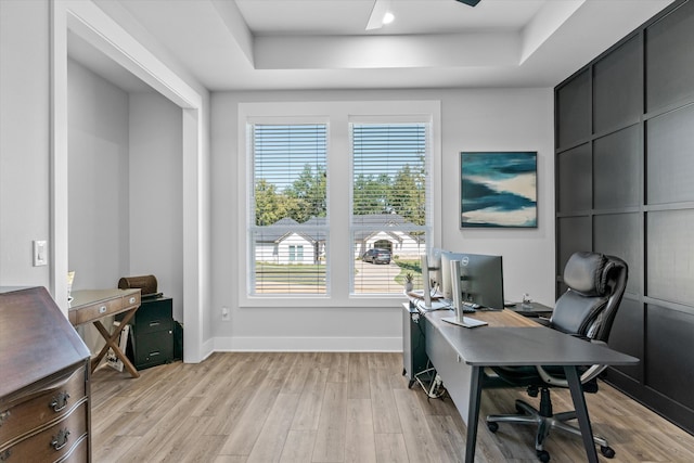 office featuring light wood-type flooring and a raised ceiling