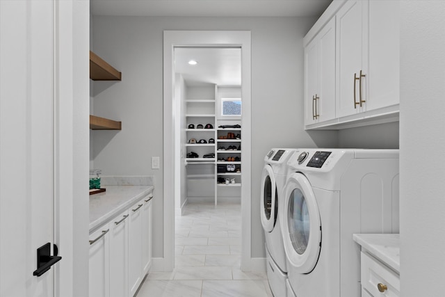 clothes washing area featuring cabinets and washer and dryer