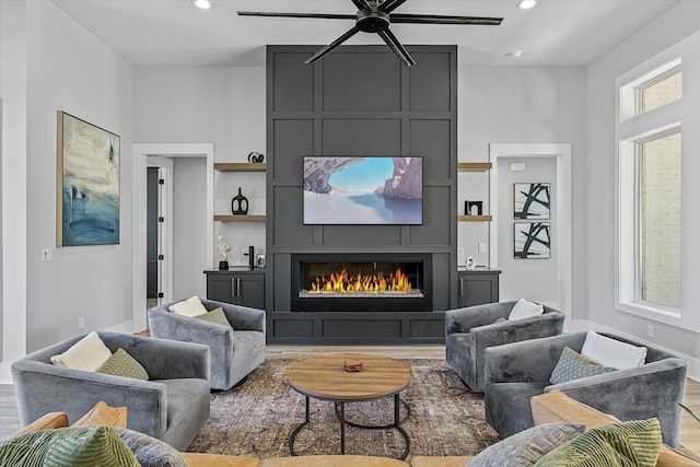 living room featuring a fireplace, light hardwood / wood-style floors, and ceiling fan