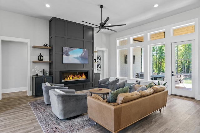 living room with a large fireplace, wood-type flooring, and ceiling fan