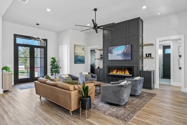 living room with light hardwood / wood-style flooring, french doors, a high ceiling, and a fireplace