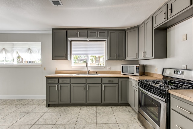 kitchen with gray cabinetry, appliances with stainless steel finishes, sink, a textured ceiling, and light tile patterned floors