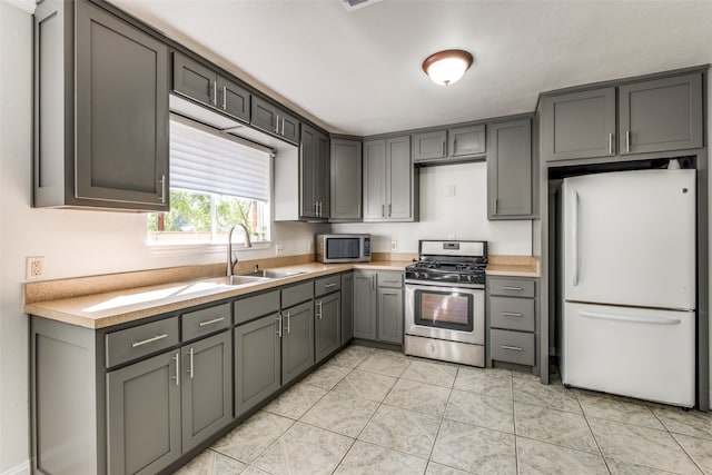 kitchen featuring gray cabinetry, light tile patterned floors, stainless steel appliances, and sink