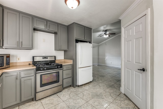 kitchen featuring a textured ceiling, ceiling fan, stainless steel appliances, gray cabinets, and ornamental molding