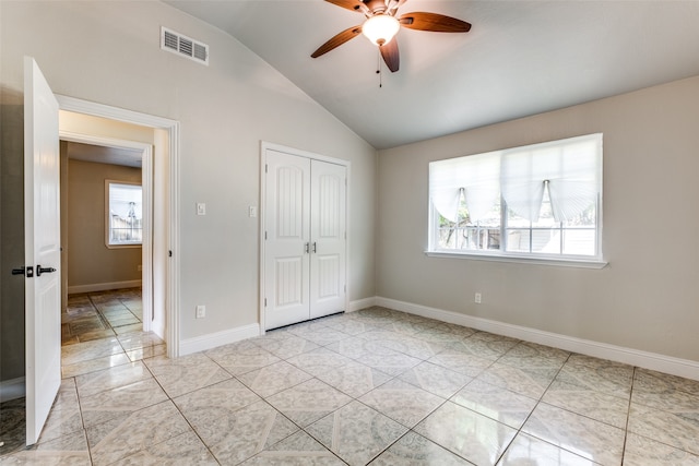 unfurnished bedroom with vaulted ceiling, light tile patterned flooring, a closet, and ceiling fan