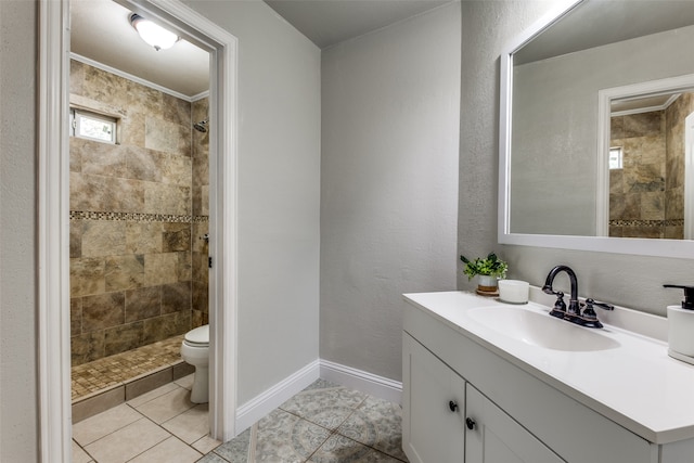 bathroom with toilet, vanity, tile patterned floors, and tiled shower